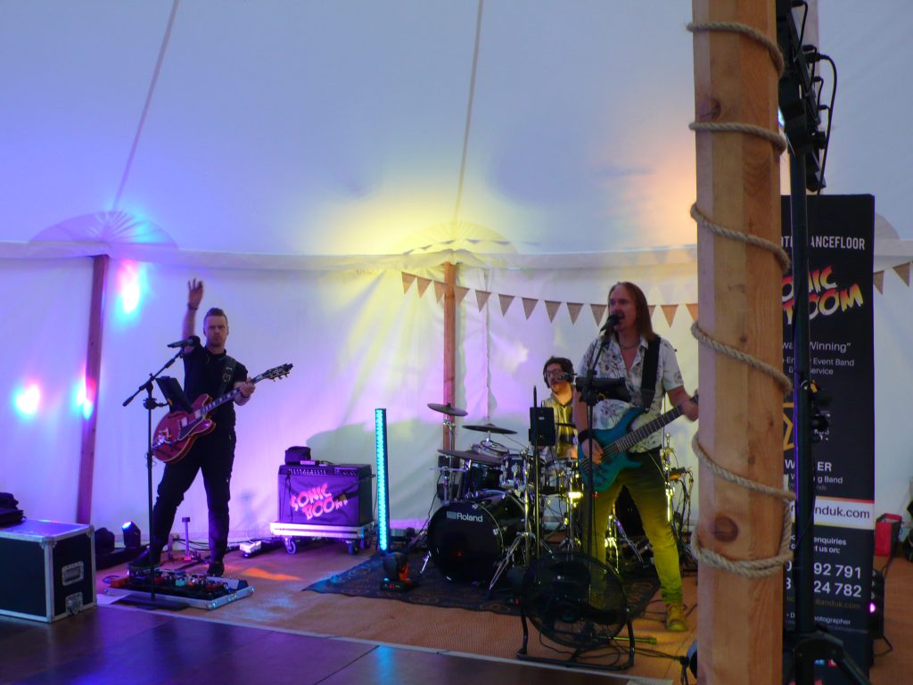 Wedding band performing under marquee lights