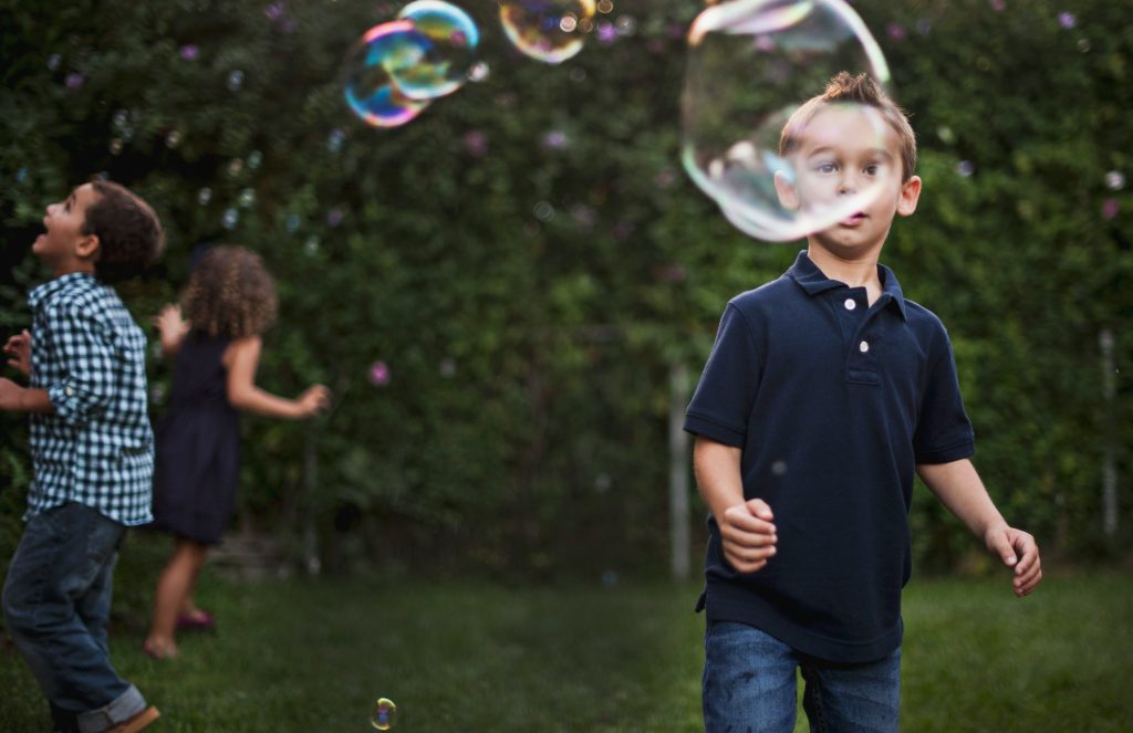 Kids blowing bubbles outside during a wedding reception.
